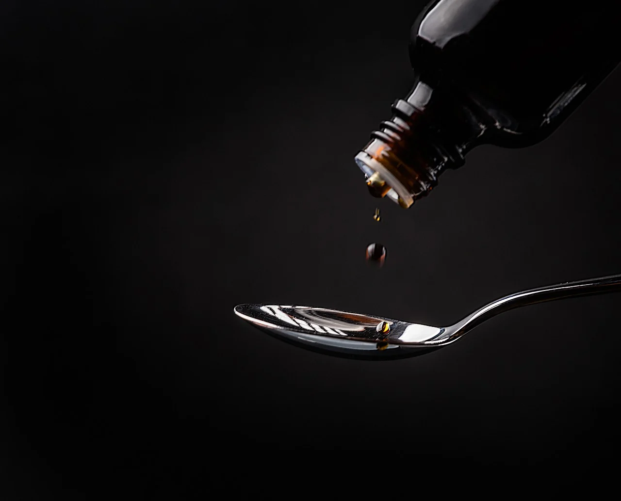 Cough syrup being measured with a spoon.