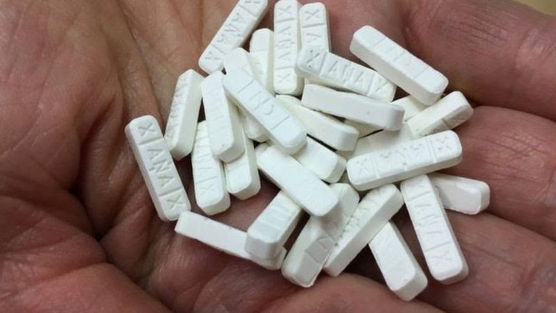 A Xanax addict holds a handful of alprazolam pills to abuse.