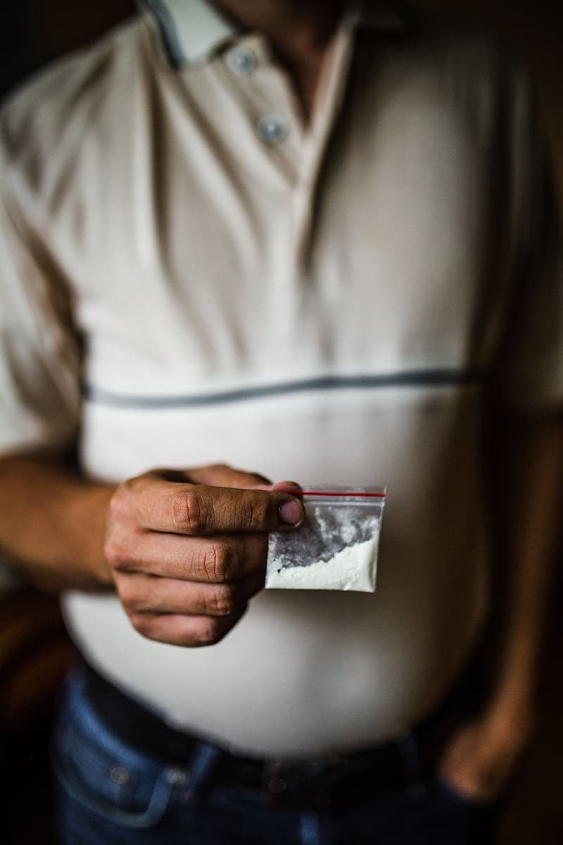 Un cocainomane con in mano un piccolo sacchetto di cocaina