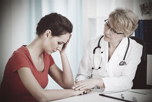 Un medico conforta una donna che ha danni al fegato a causa dell'uso prolungato di eroina.